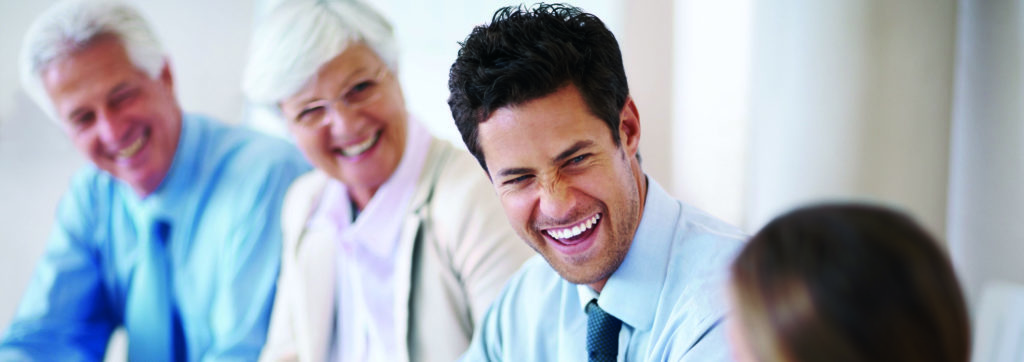 Smart young businessman smiling while sitting in a meeting with his colleagues